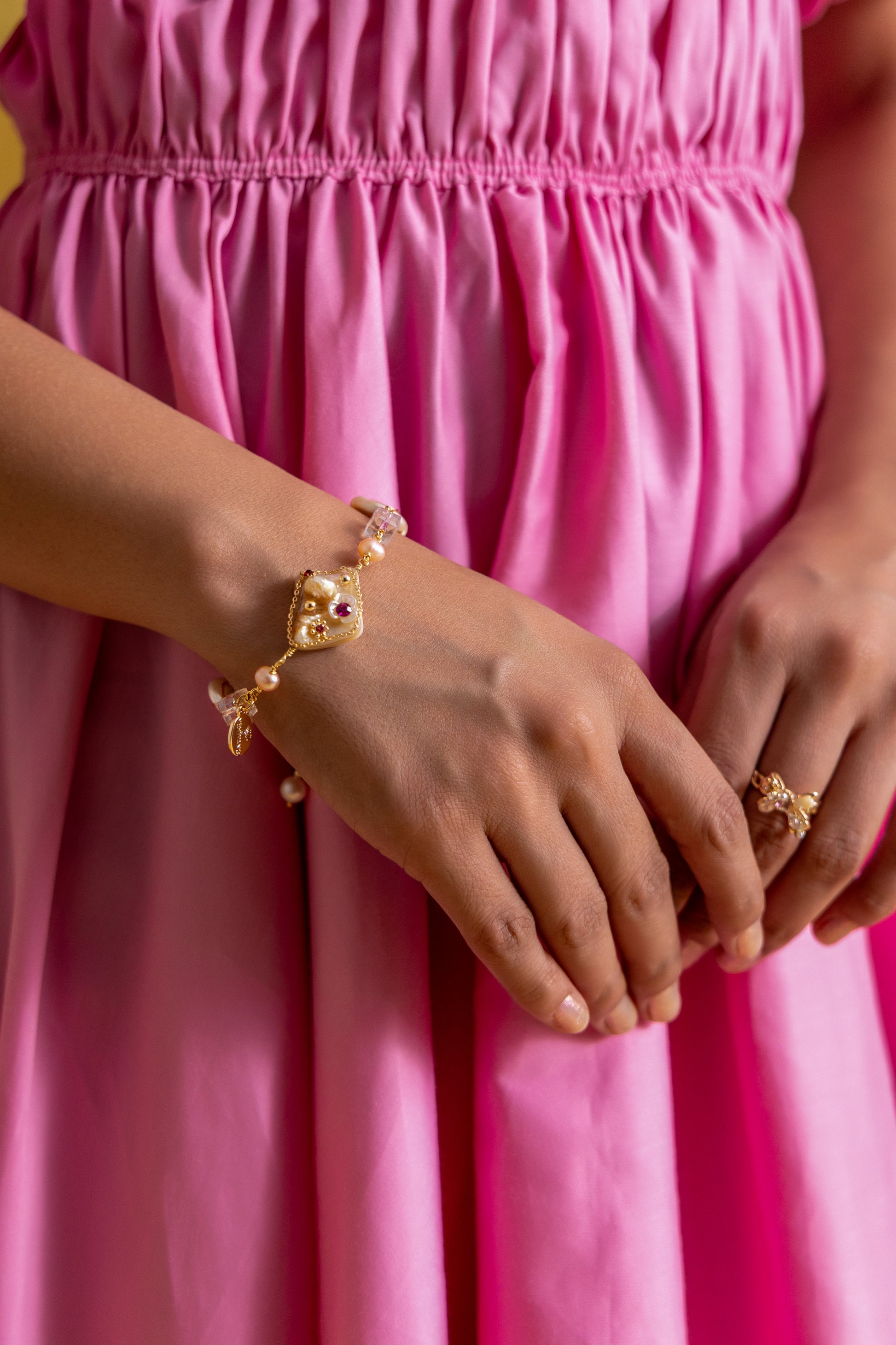 "Royal Whimsy Pearl Bracelet with a crown-inspired gold centerpiece, soft pink pearls, and crystal accents, blending vintage charm with modern elegance."
