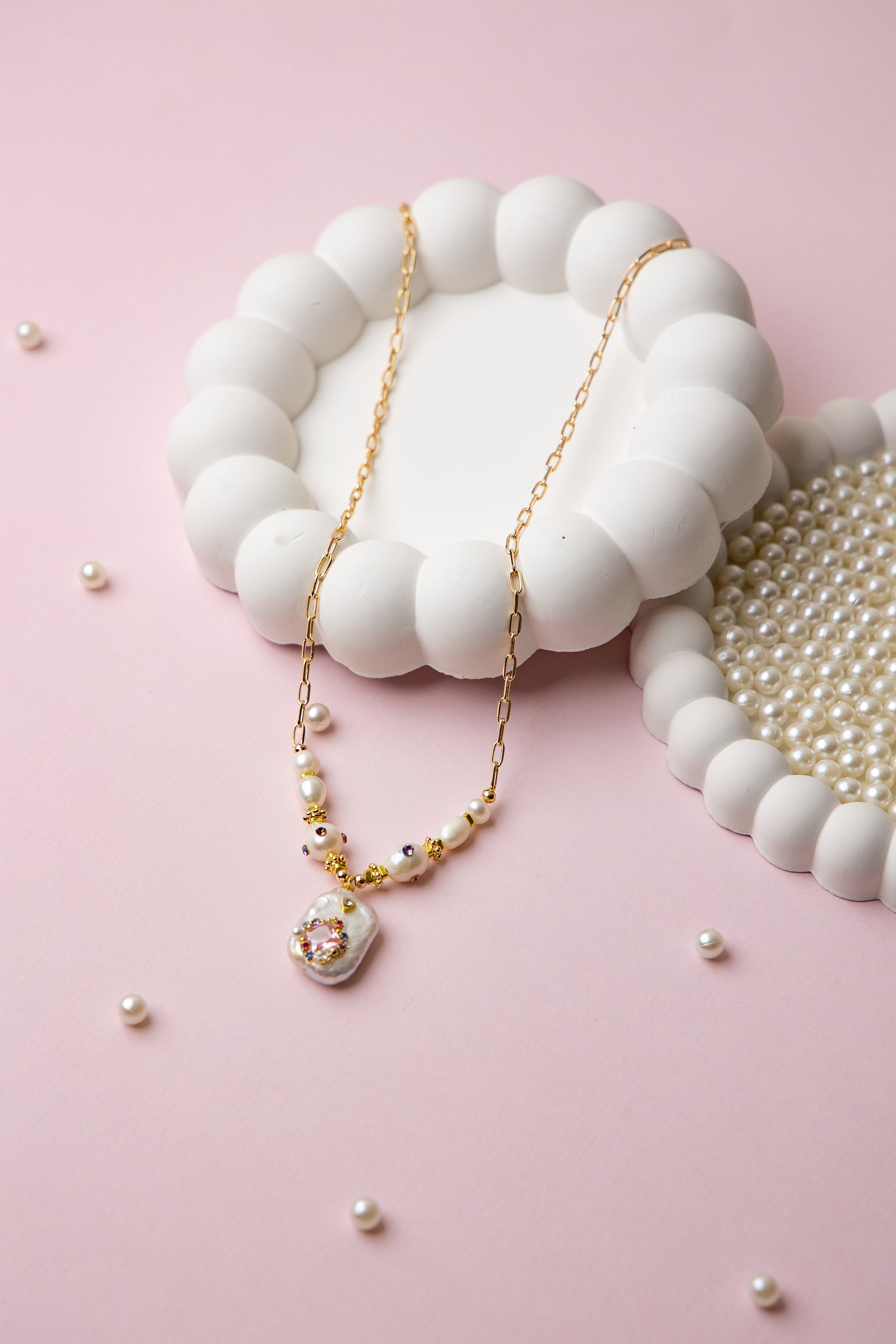 A bold necklace with large baroque seawater pearls and a central floral design, connected by a textured gold chain. Ideal for statement looks.