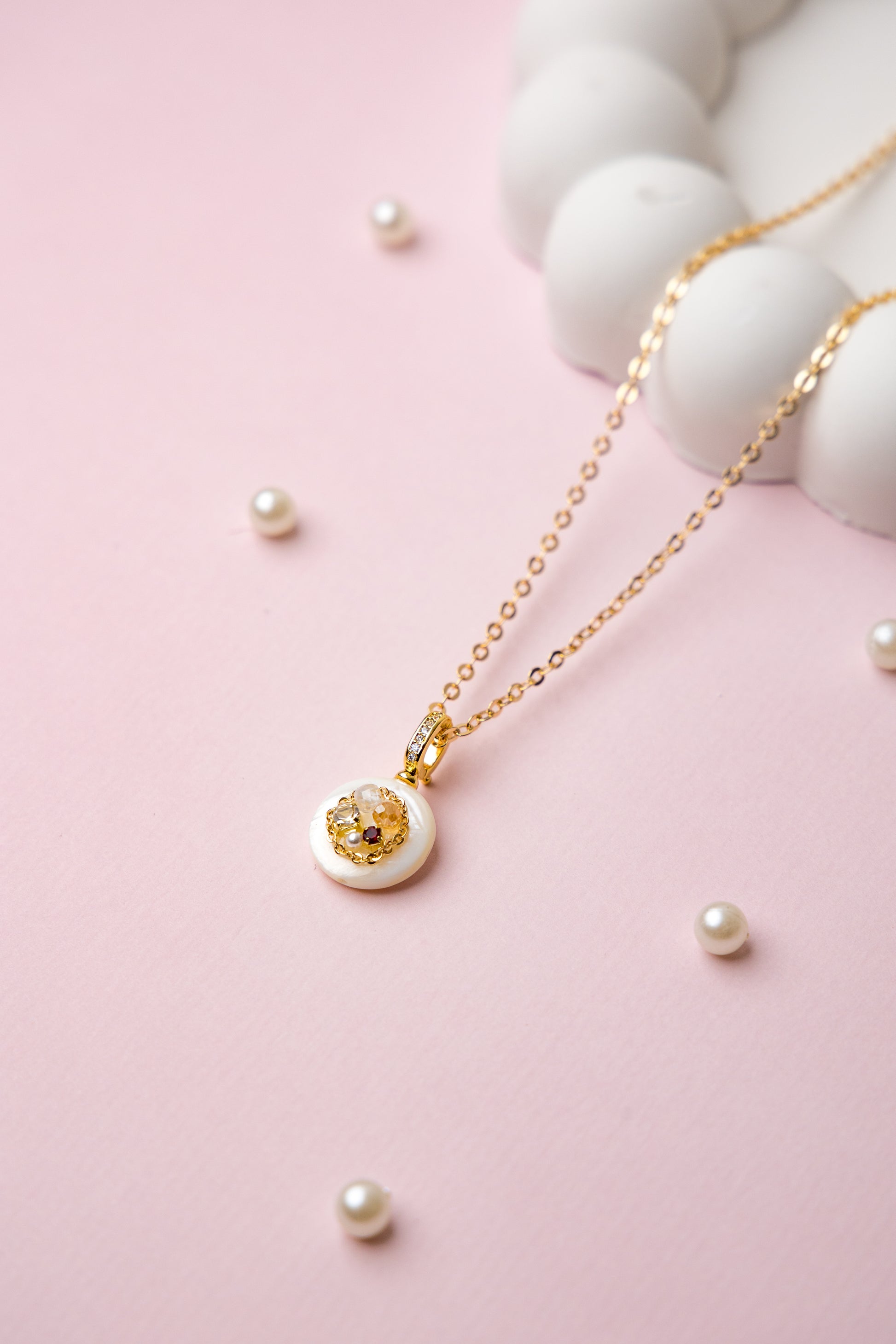 A delicate gold-tone chain necklace featuring a minimalist white resin pendant with embedded stones. Perfect for daily wear and subtle elegance.
