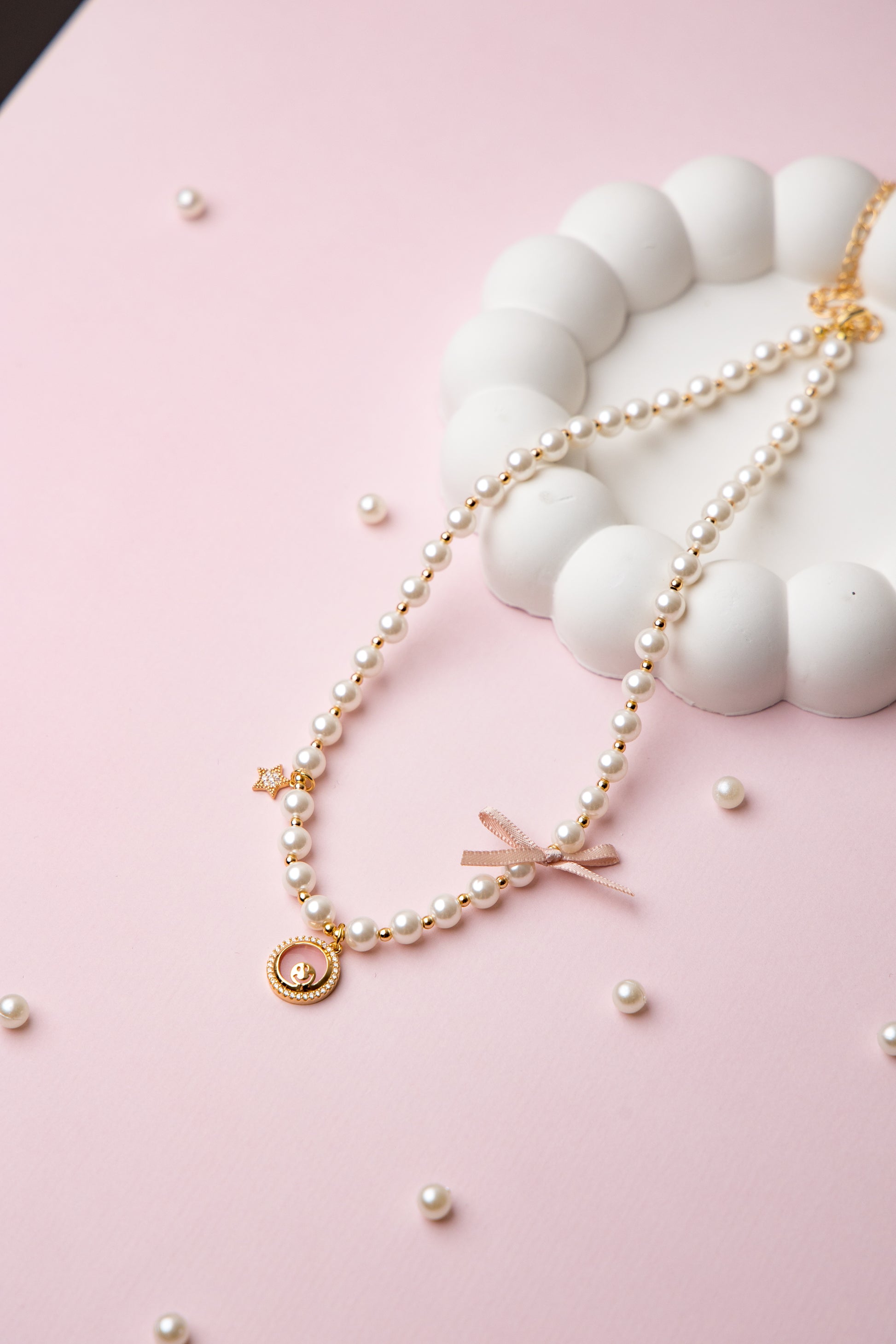 A romantic pearl necklace accented with a soft pink enamel rose charm and a satin bow. Feminine and perfect for gifting.