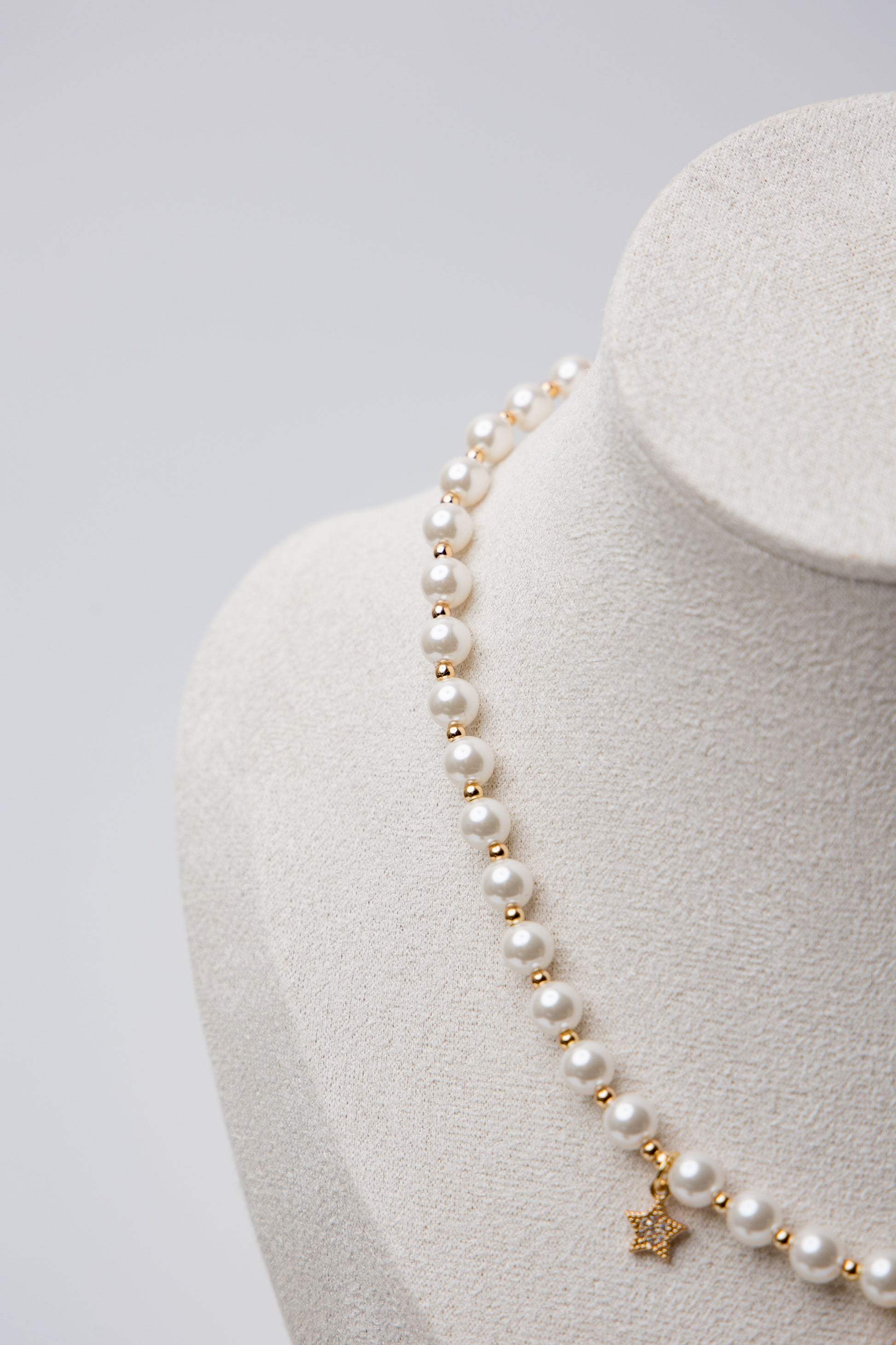 A romantic pearl necklace accented with a soft pink enamel rose charm and a satin bow. Feminine and perfect for gifting.