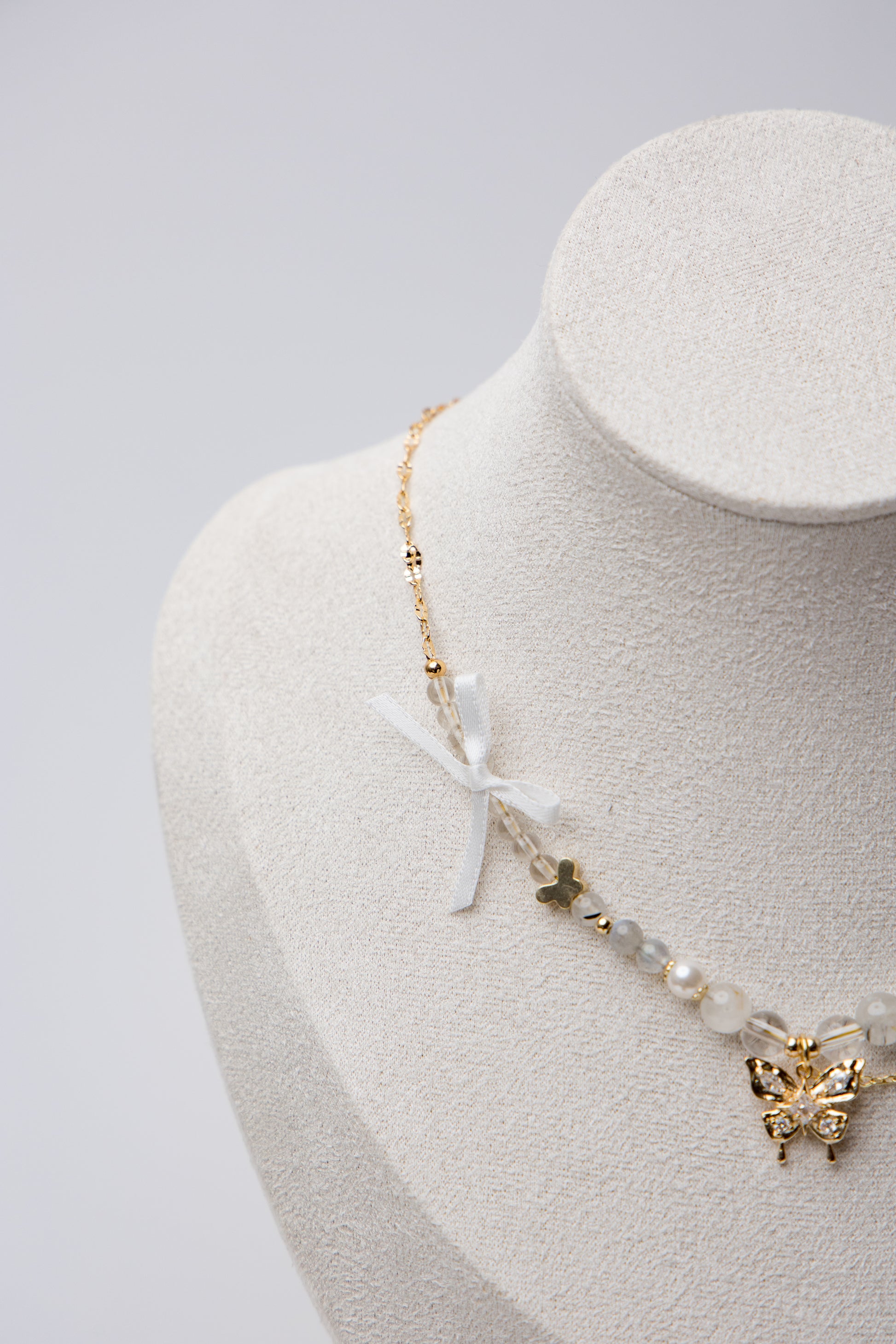 Layered Butterfly Charm Necklace with a two-layer chain featuring a crystal-studded butterfly, star charm, ribbon detail, and a small black bead for a whimsical, graceful look.