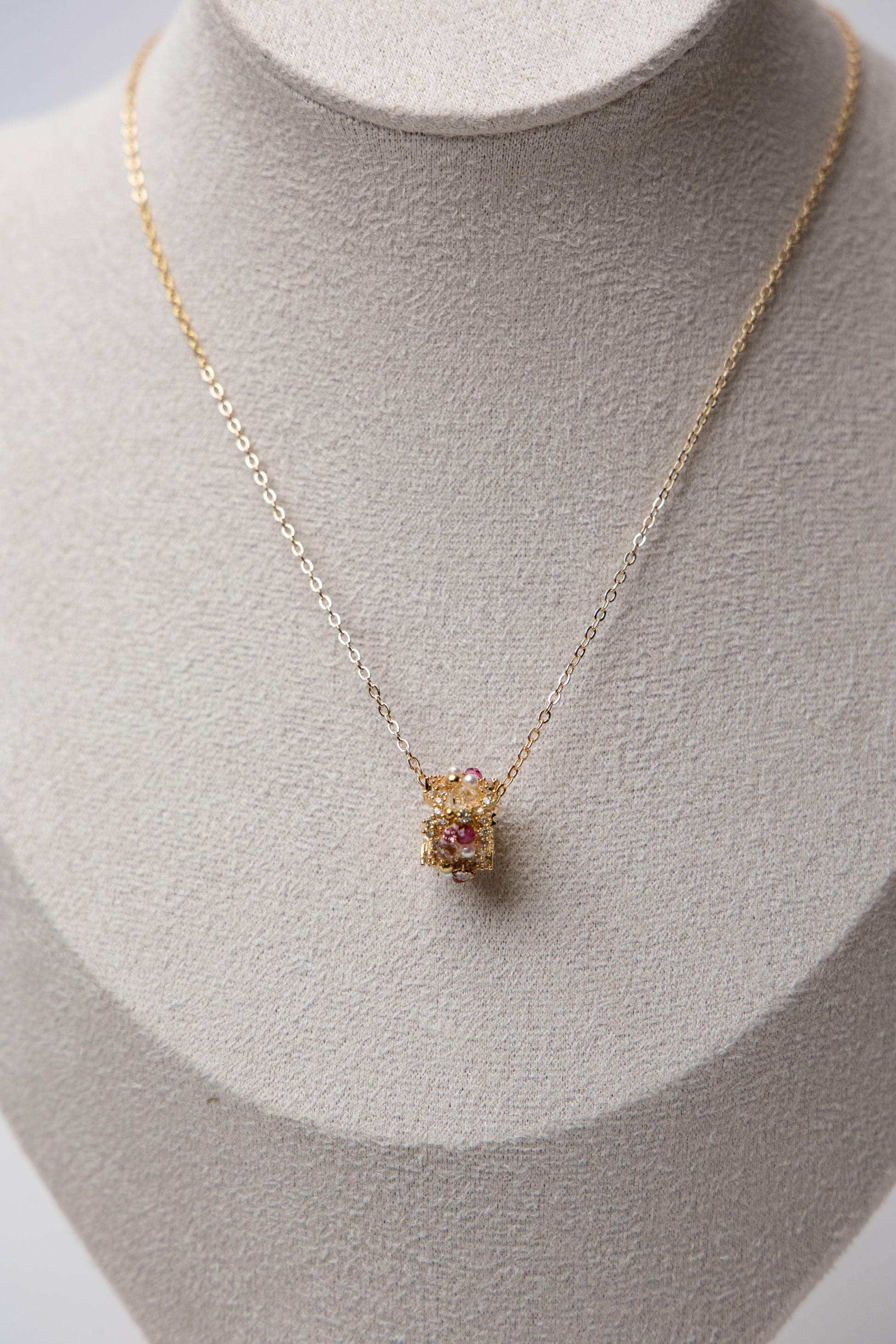 A gold-tone chain necklace with a central floral bead cluster, featuring crystals and delicate craftsmanship.