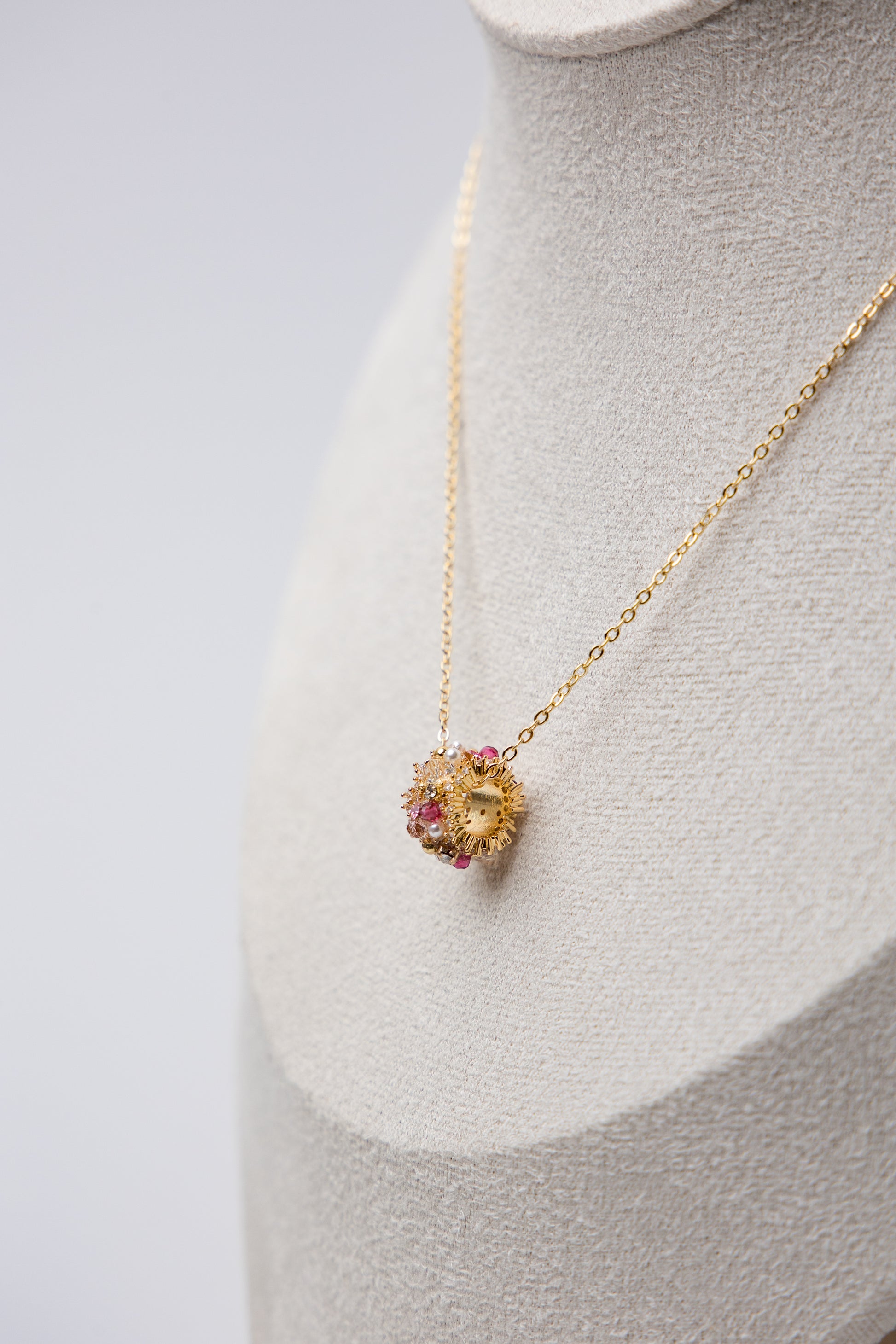 A gold-tone chain necklace with a central floral bead cluster, featuring crystals and delicate craftsmanship.