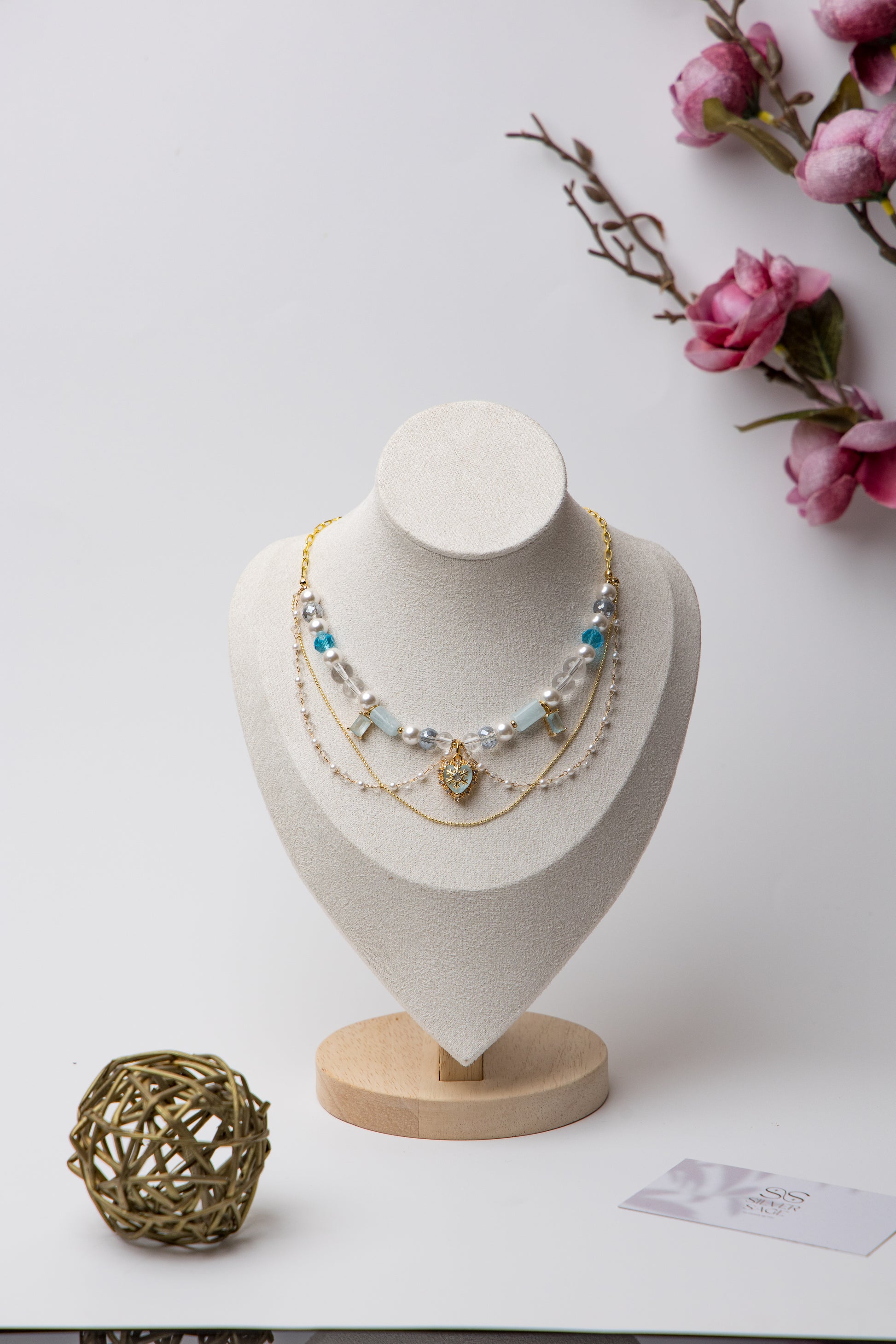 A statement piece with icy blue beads, layered pearls, and a snowflake heart charm