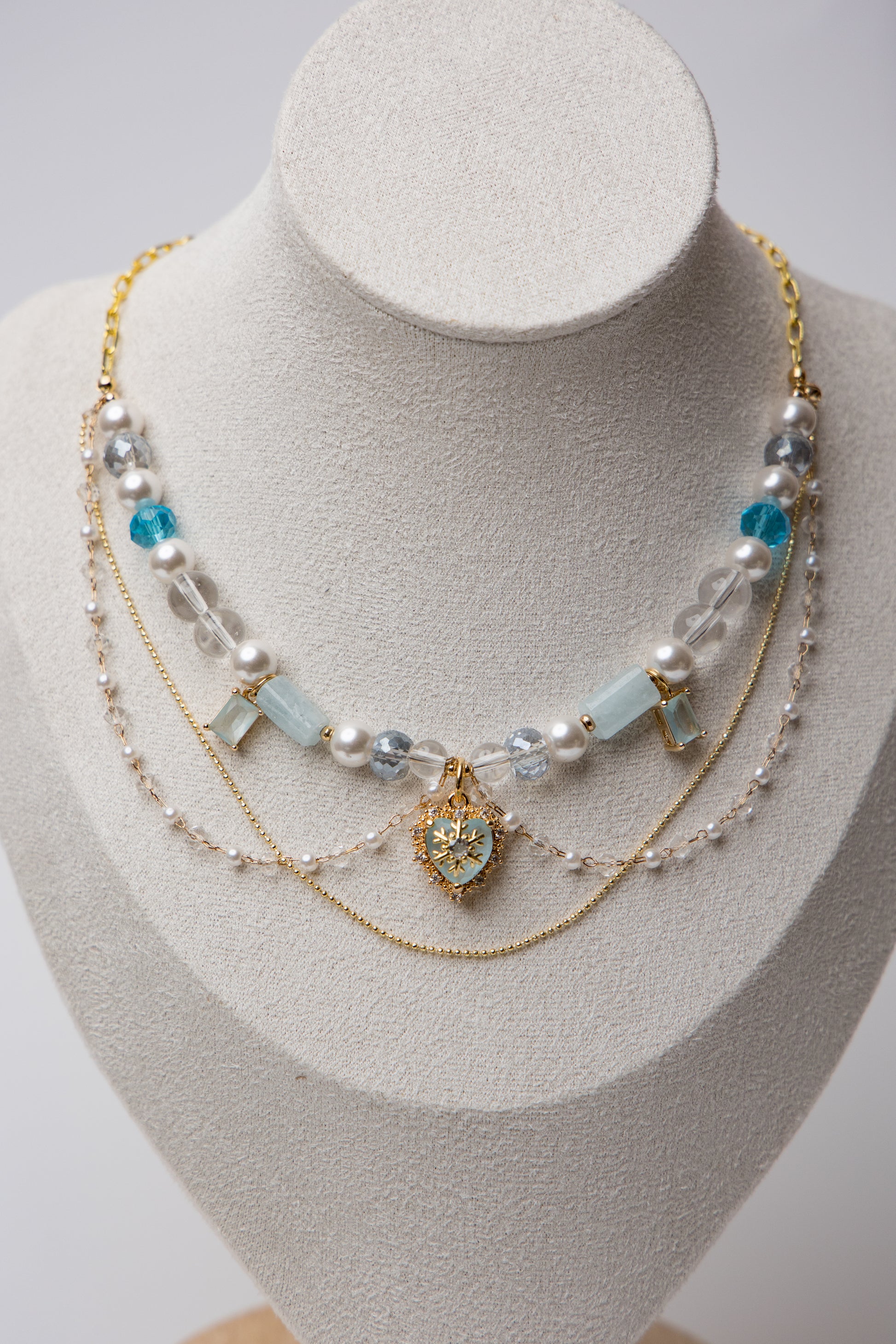 A statement piece with icy blue beads, layered pearls, and a snowflake heart charm