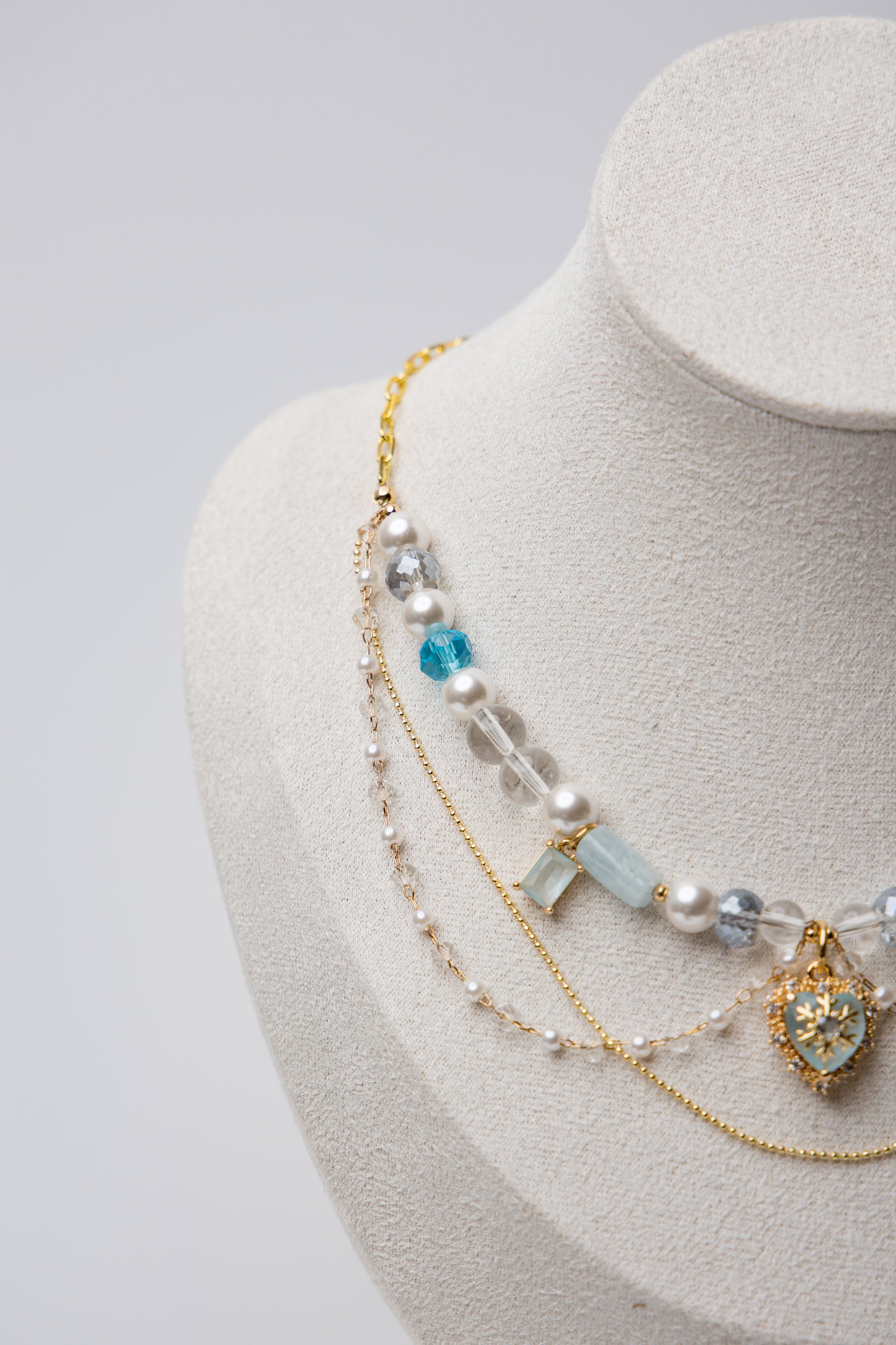 A statement piece with icy blue beads, layered pearls, and a snowflake heart charm