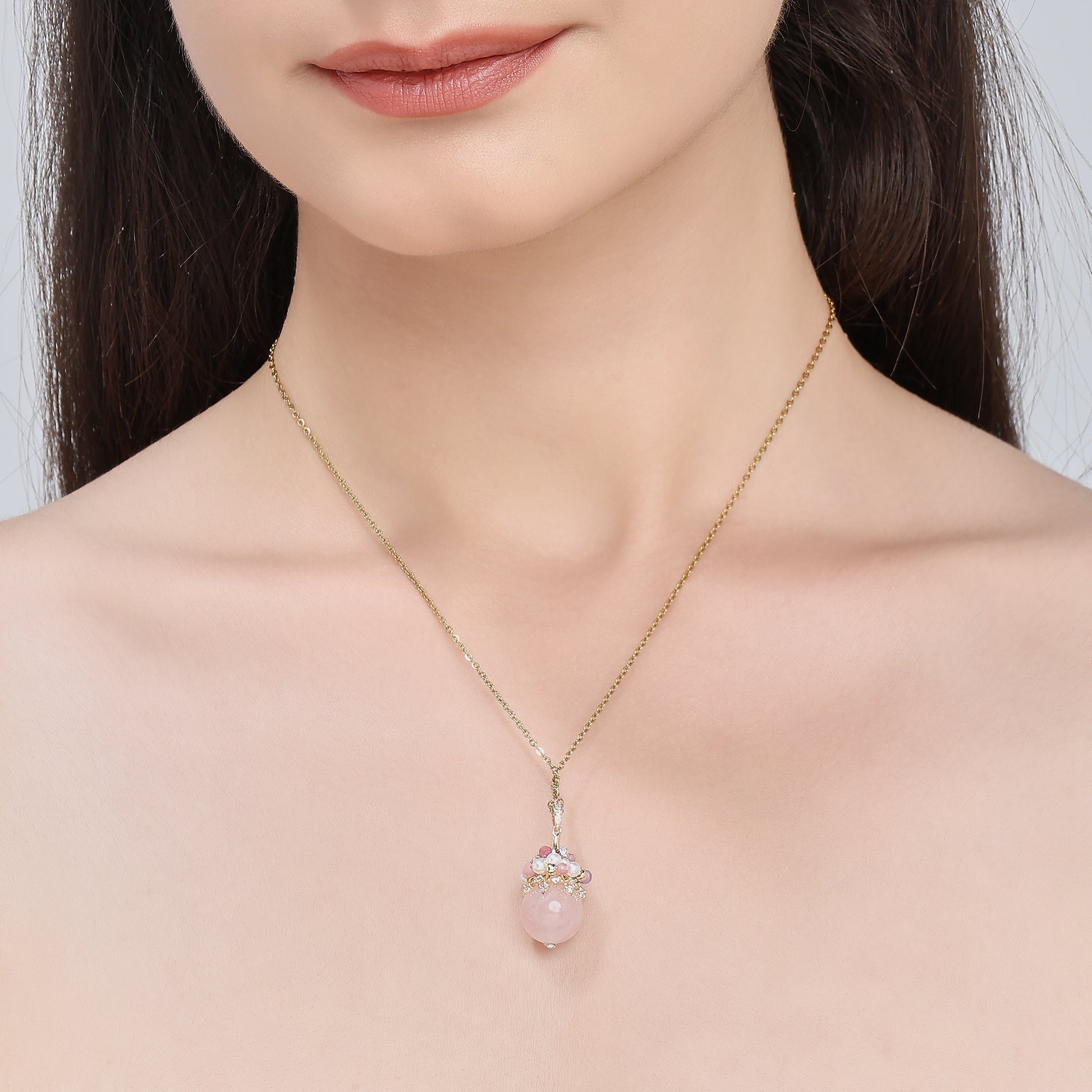 Close-up of an elegant necklace featuring a soft pink rose quartz orb, accented with a cluster of luminous freshwater pearls and deep pink tourmaline beads, evoking charm, femininity, and grace.