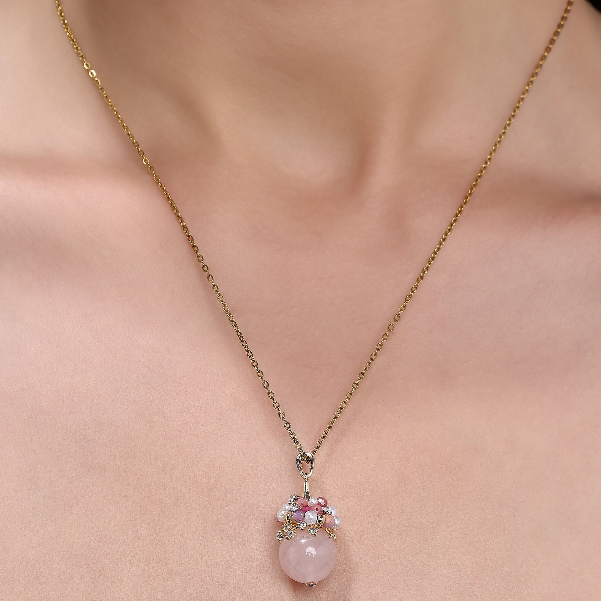 Close-up of an elegant necklace featuring a soft pink rose quartz orb, accented with a cluster of luminous freshwater pearls and deep pink tourmaline beads, evoking charm, femininity, and grace.
