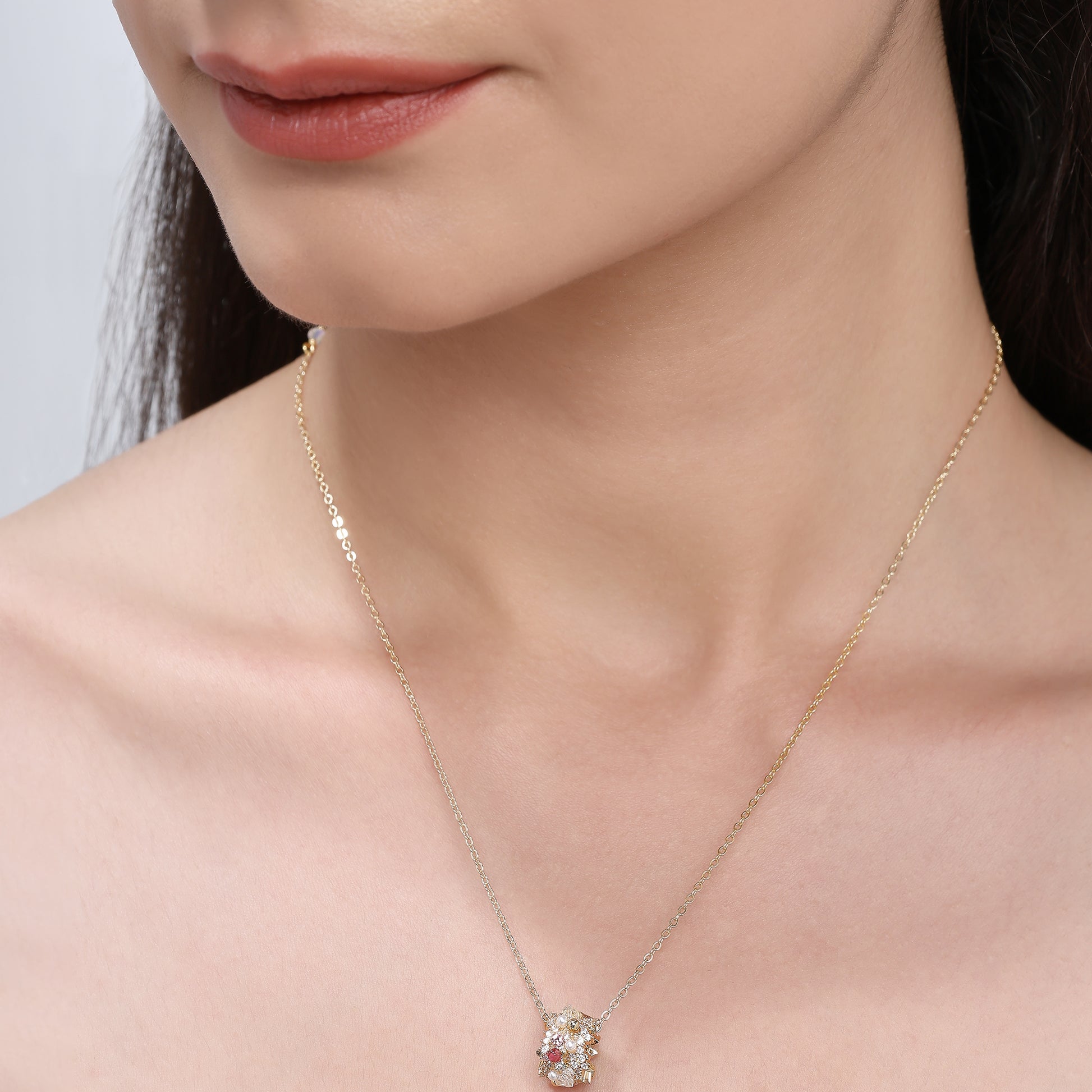A gold-tone chain necklace with a central floral bead cluster, featuring crystals and delicate craftsmanship.