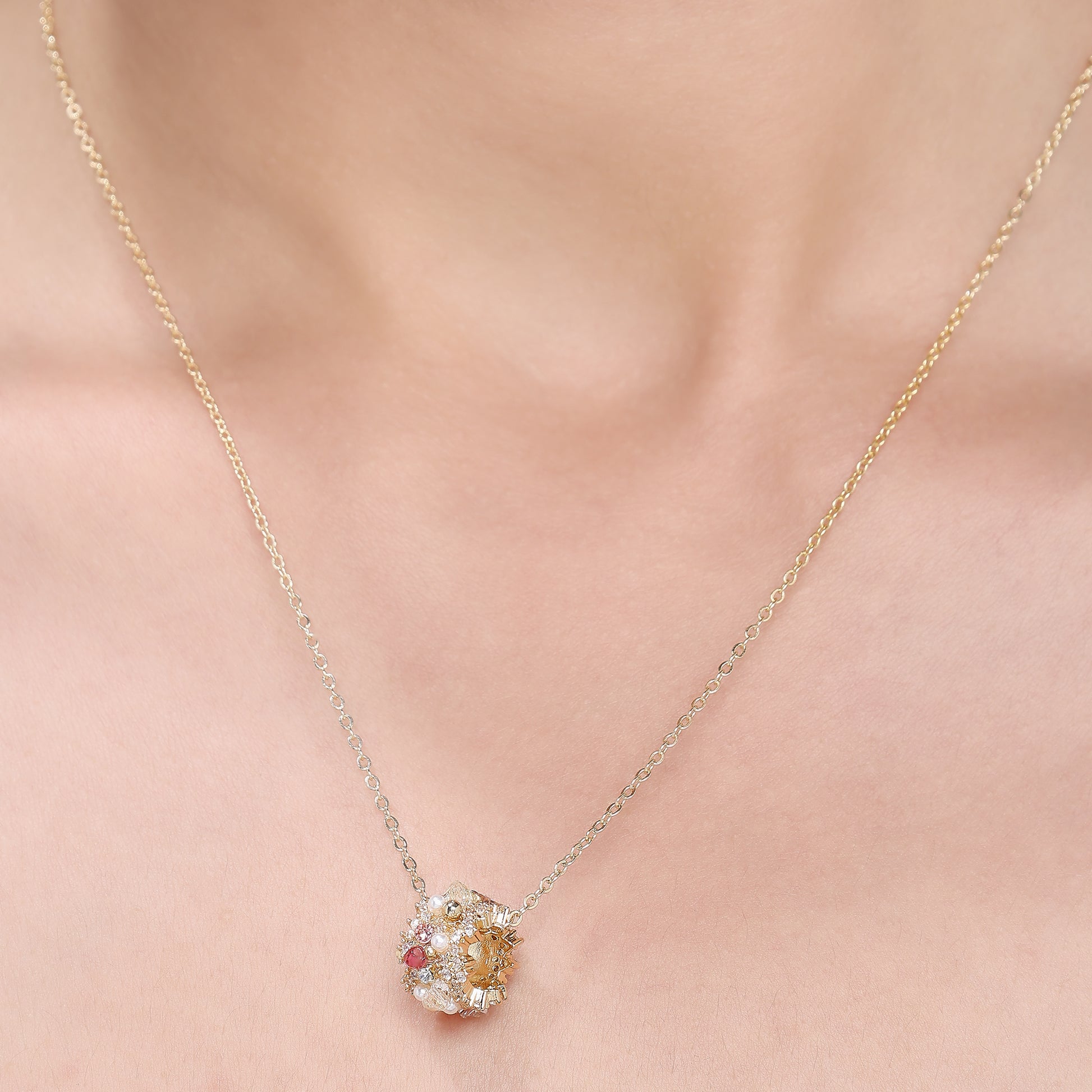 A gold-tone chain necklace with a central floral bead cluster, featuring crystals and delicate craftsmanship.