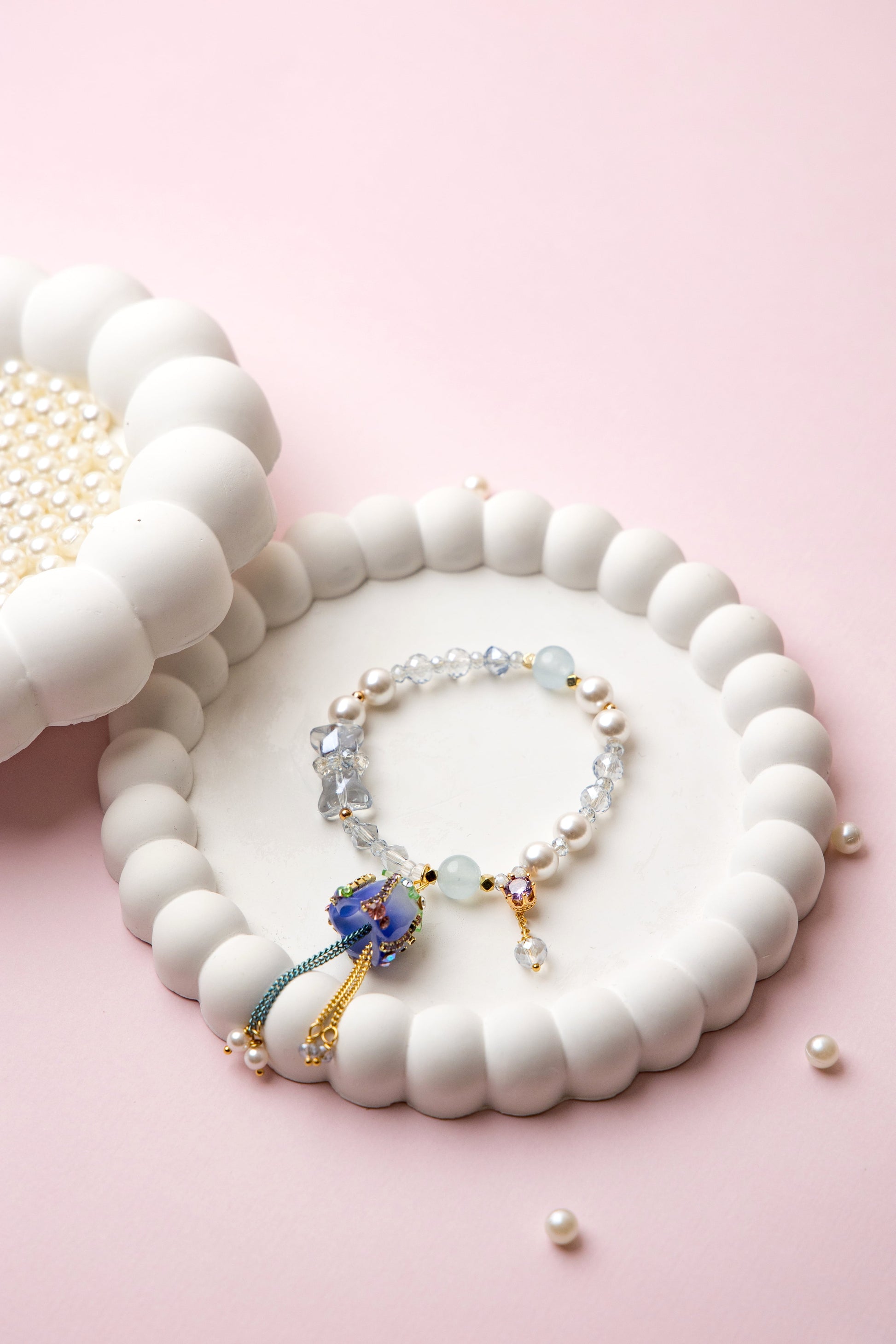 Featuring an elegant blue rose charm with pearl & aquamarine beads and flowing tassel accent.