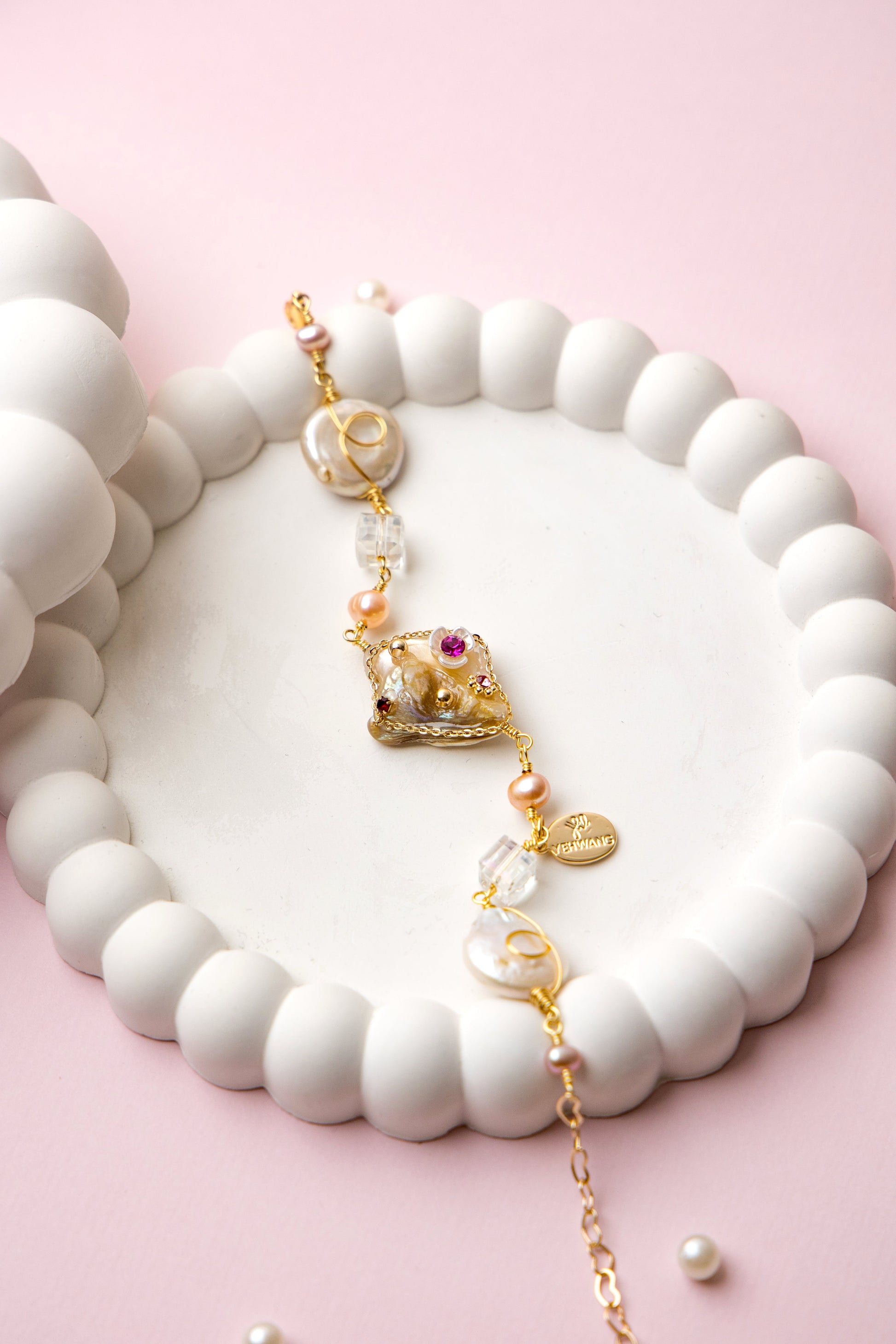 "Royal Whimsy Pearl Bracelet with a crown-inspired gold centerpiece, soft pink pearls, and crystal accents, blending vintage charm with modern elegance."