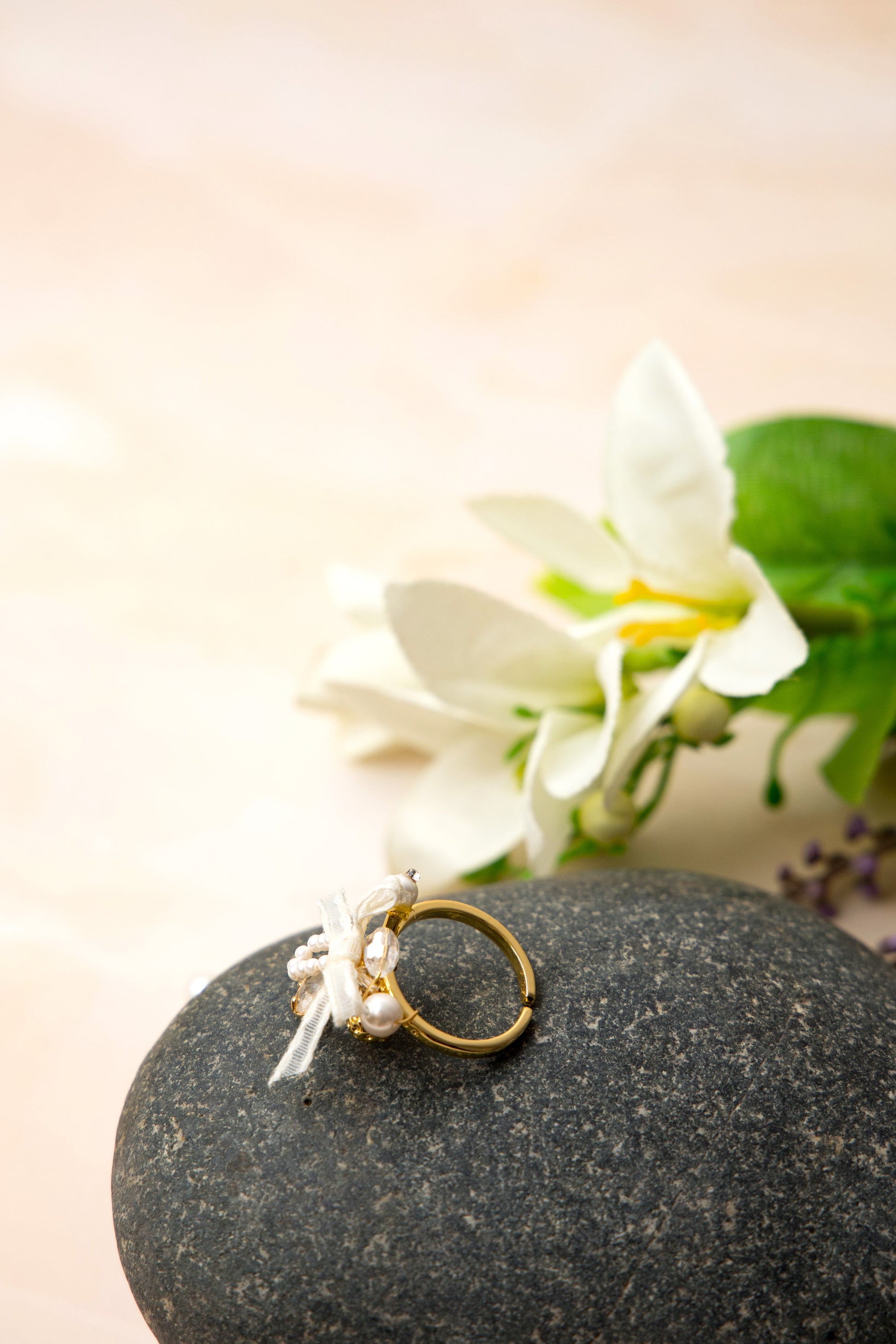 A romantic gold-tone ring showcasing a clear heart-shaped stone framed by tiny faux pearls in an arch, adorned with an ivory organza ribbon bow and a faceted bead for added sparkle and vintage charm.