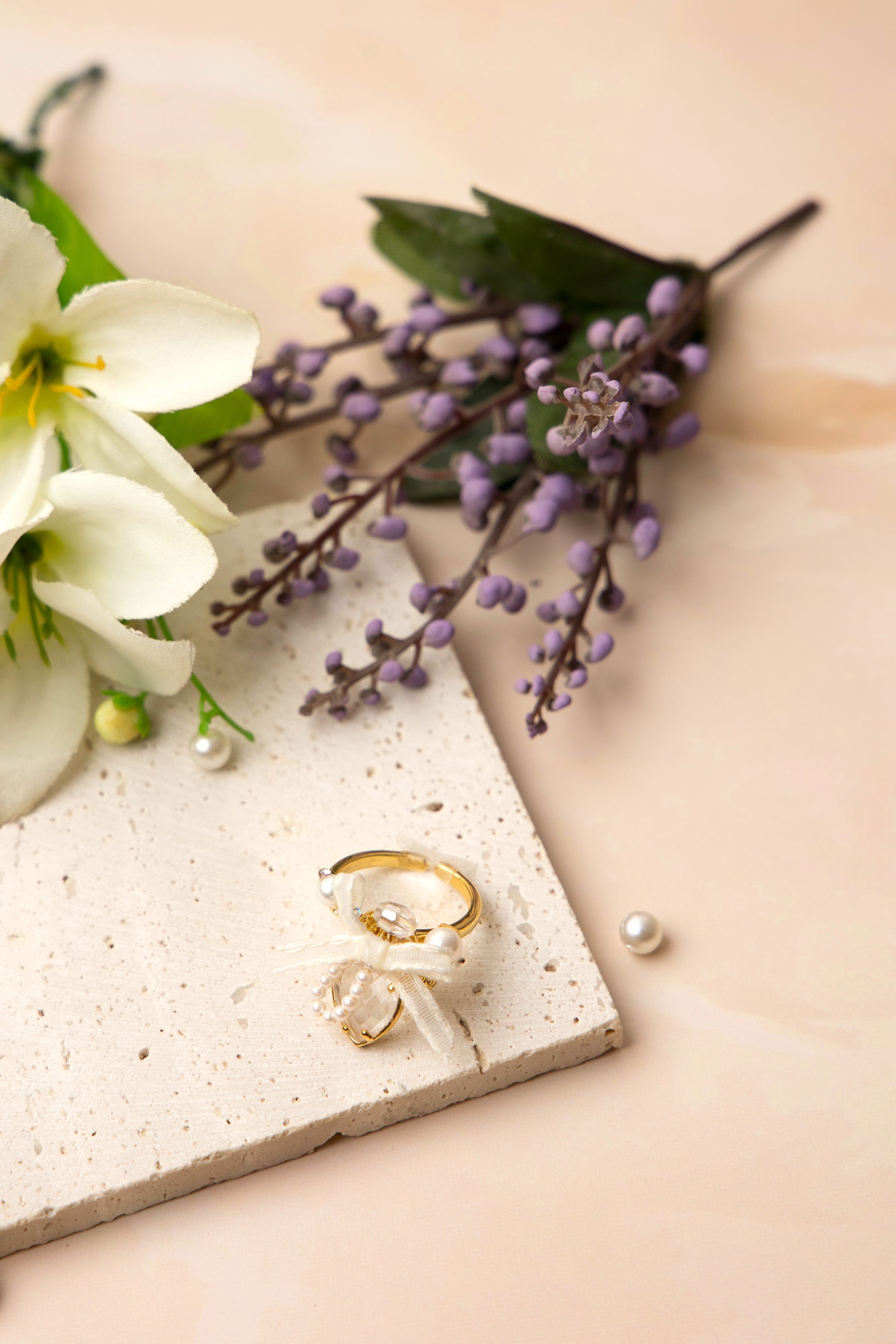 A romantic gold-tone ring showcasing a clear heart-shaped stone framed by tiny faux pearls in an arch, adorned with an ivory organza ribbon bow and a faceted bead for added sparkle and vintage charm.