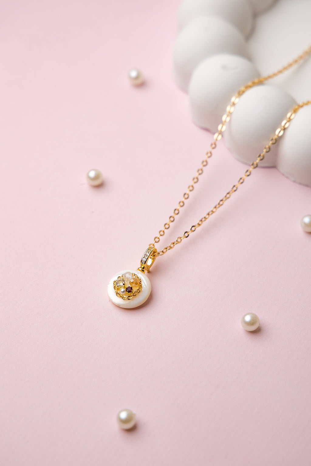 A delicate gold-tone chain necklace featuring a minimalist white resin pendant with embedded stones. Perfect for daily wear and subtle elegance.