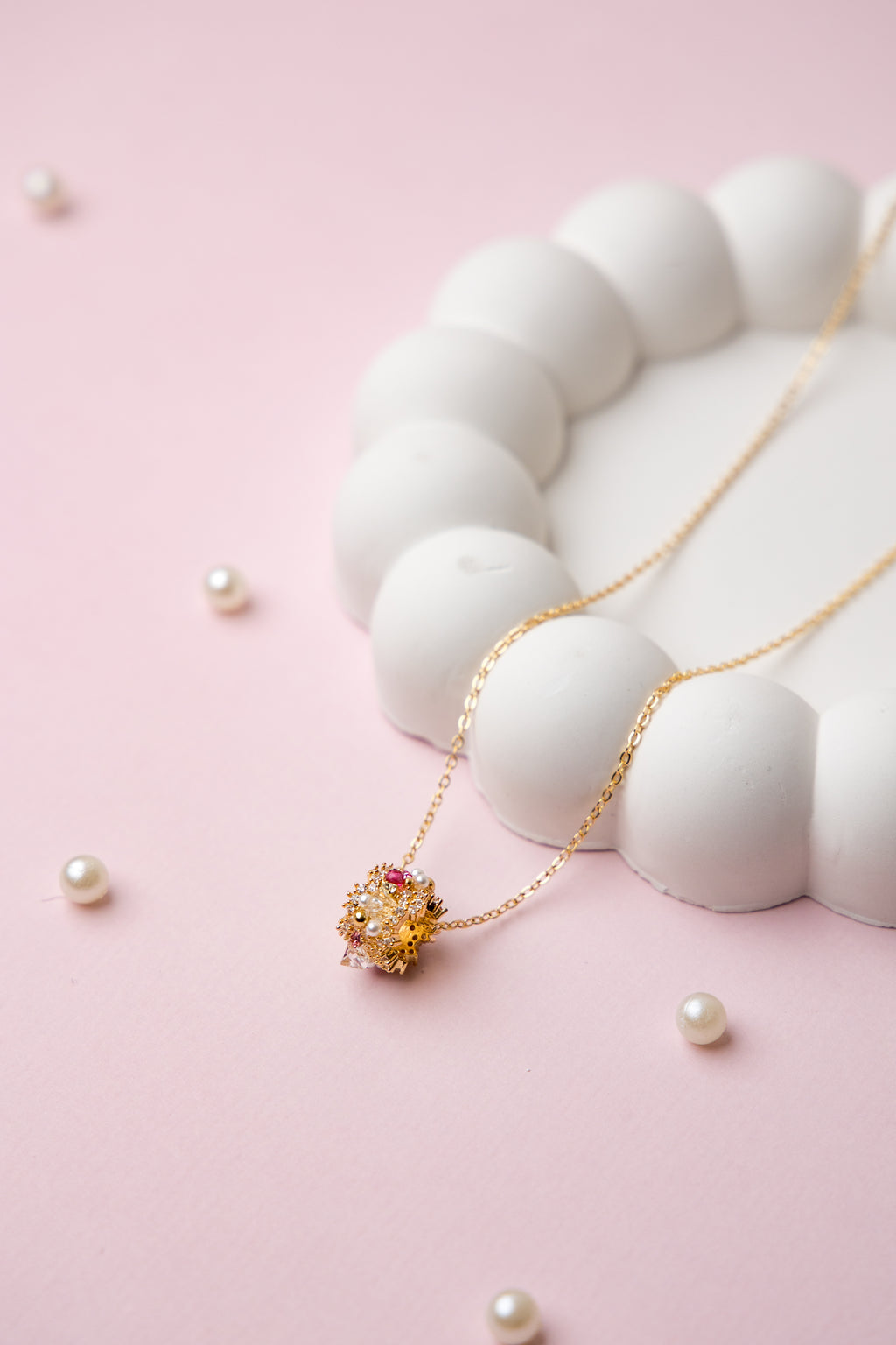 A gold-tone chain necklace with a central floral bead cluster, featuring crystals and delicate craftsmanship.