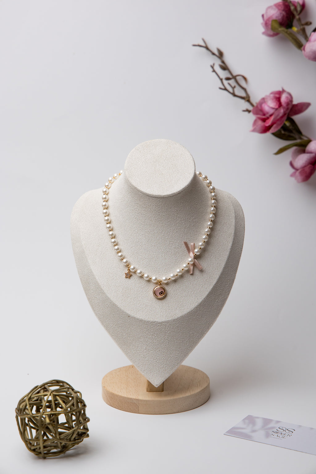 A romantic pearl necklace accented with a soft pink enamel rose charm and a satin bow. Feminine and perfect for gifting.