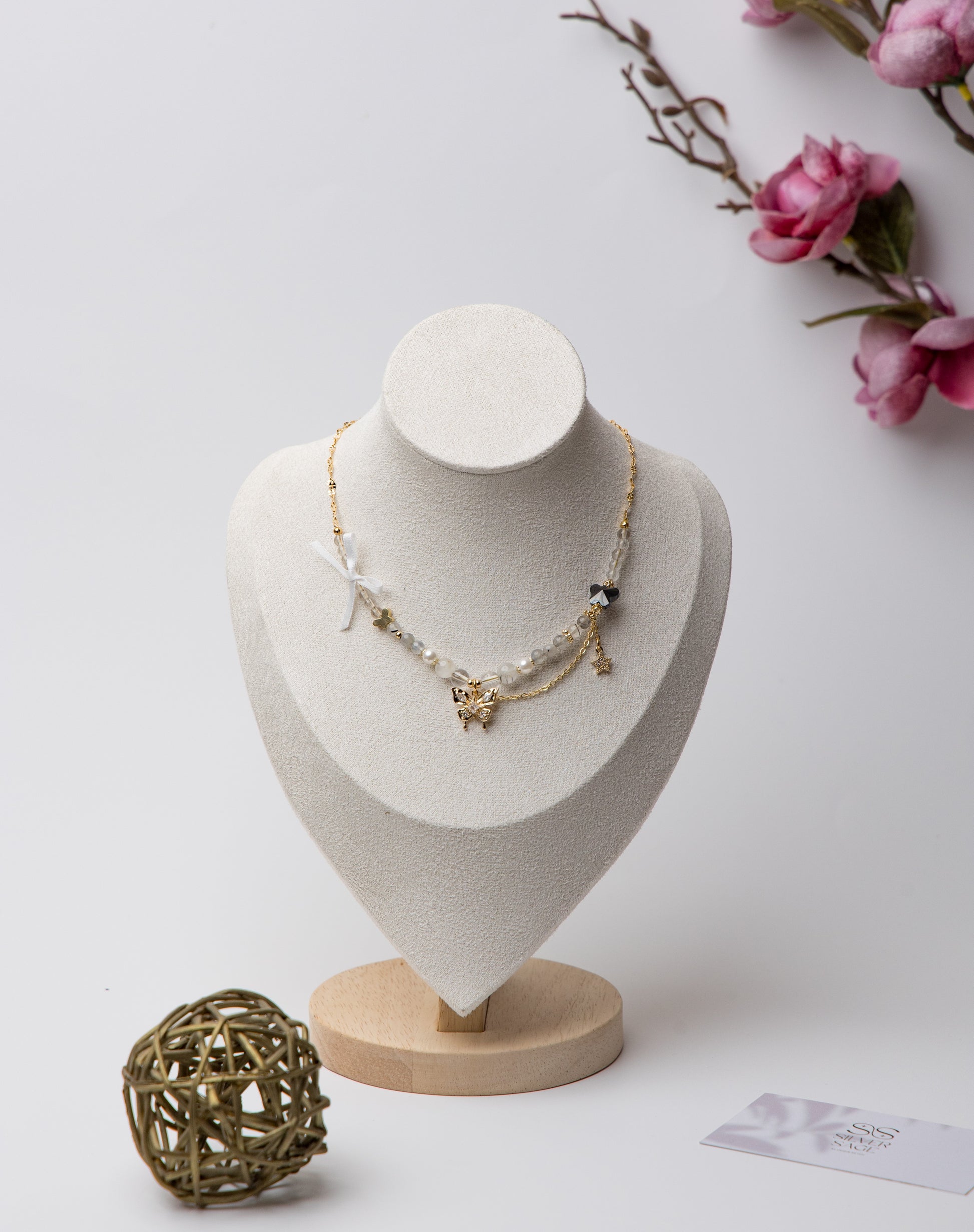 Layered Butterfly Charm Necklace with a two-layer chain featuring a crystal-studded butterfly, star charm, ribbon detail, and a small black bead for a whimsical, graceful look.