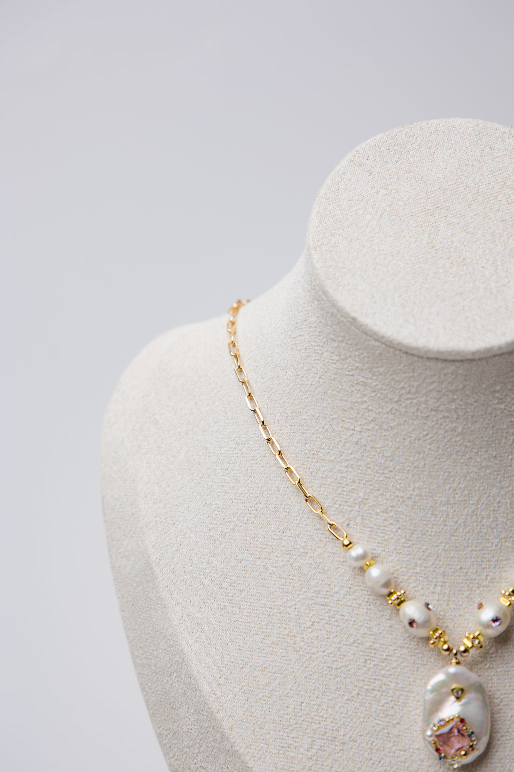 A bold necklace with large baroque seawater pearls and a central floral design, connected by a textured gold chain. Ideal for statement looks.