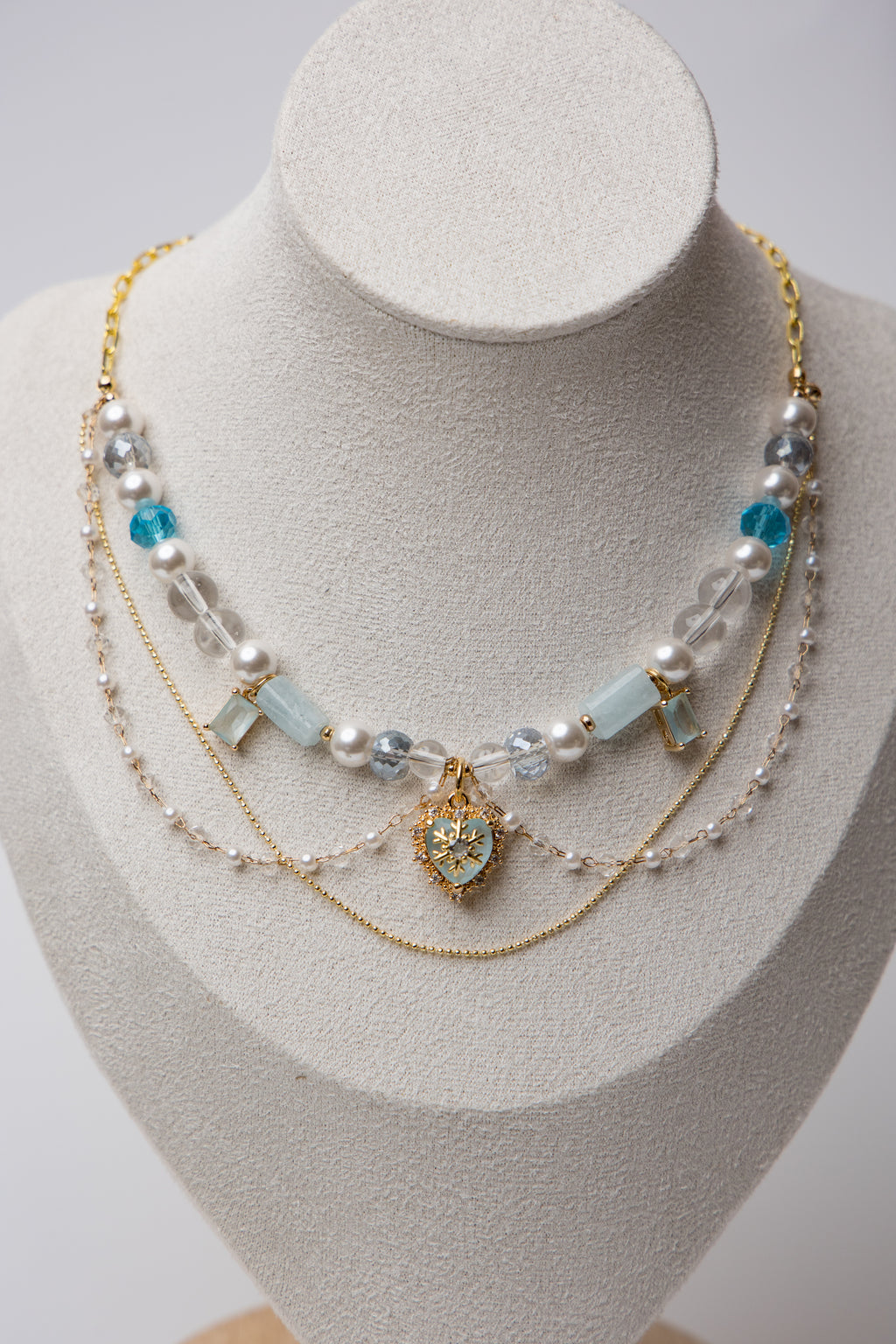 A statement piece with icy blue beads, layered pearls, and a snowflake heart charm