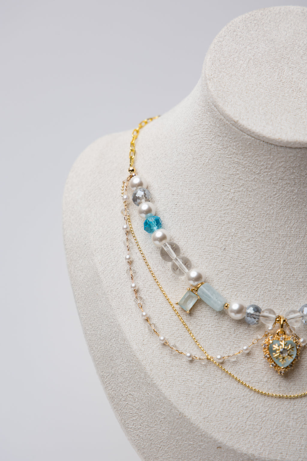 A statement piece with icy blue beads, layered pearls, and a snowflake heart charm