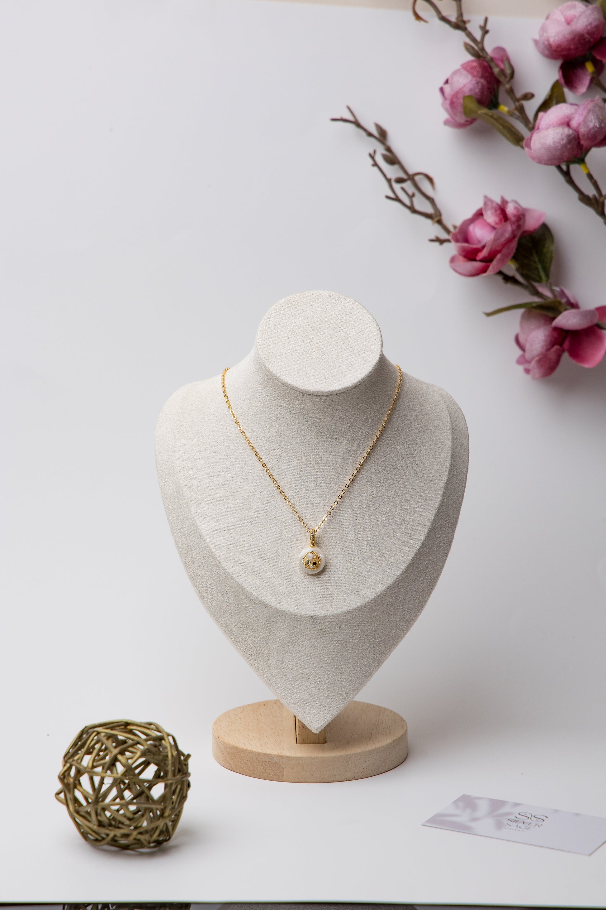 A delicate gold-tone chain necklace featuring a minimalist white resin pendant with embedded stones. Perfect for daily wear and subtle elegance.