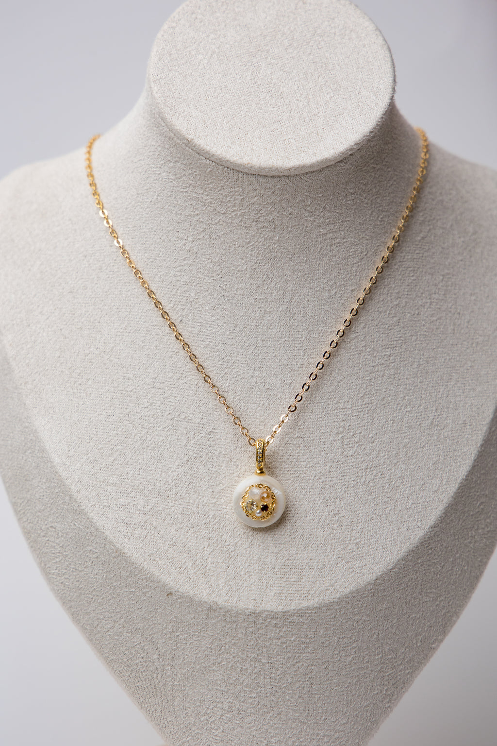 A delicate gold-tone chain necklace featuring a minimalist white resin pendant with embedded stones. Perfect for daily wear and subtle elegance.