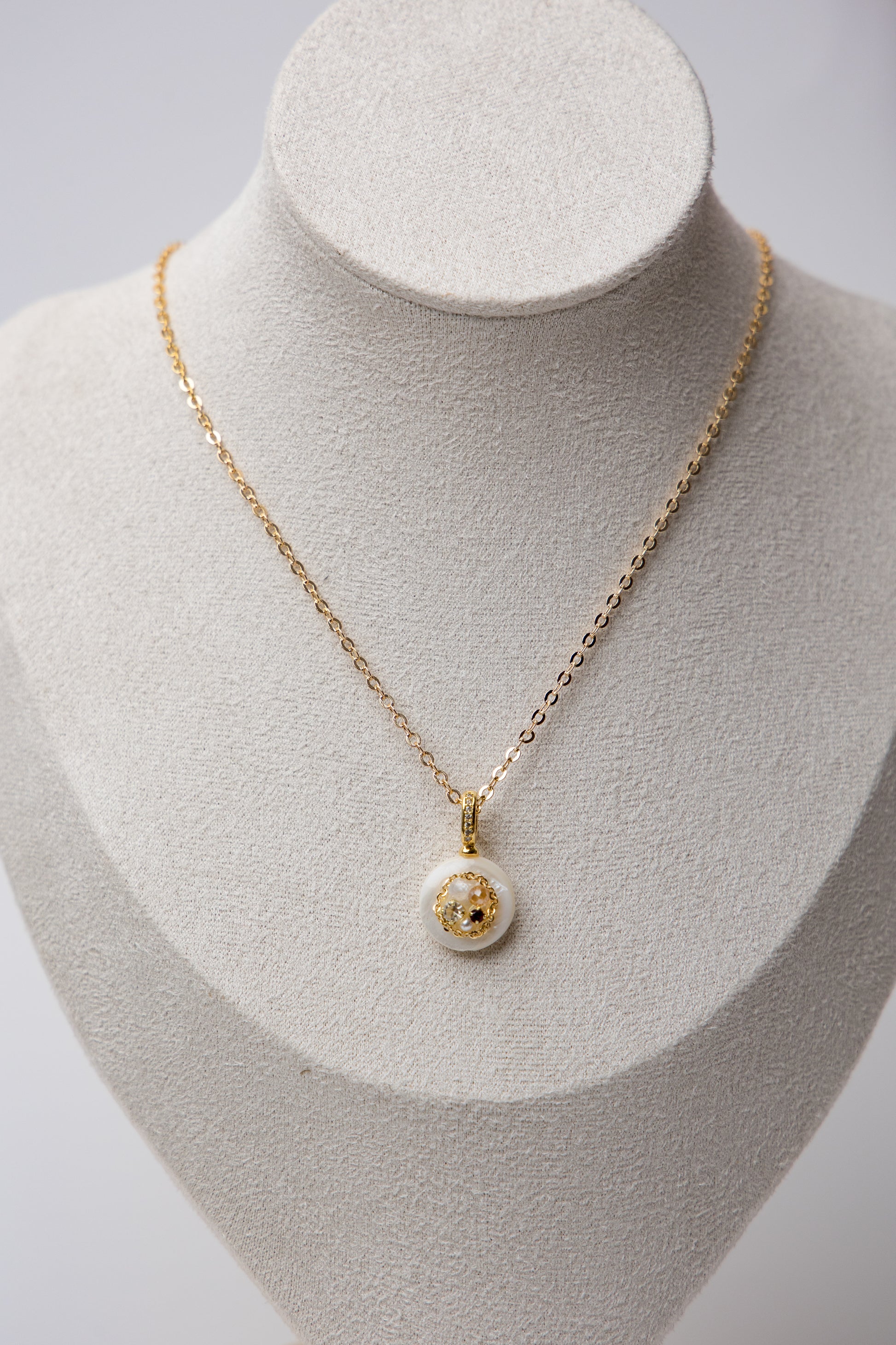 A delicate gold-tone chain necklace featuring a minimalist white resin pendant with embedded stones. Perfect for daily wear and subtle elegance.