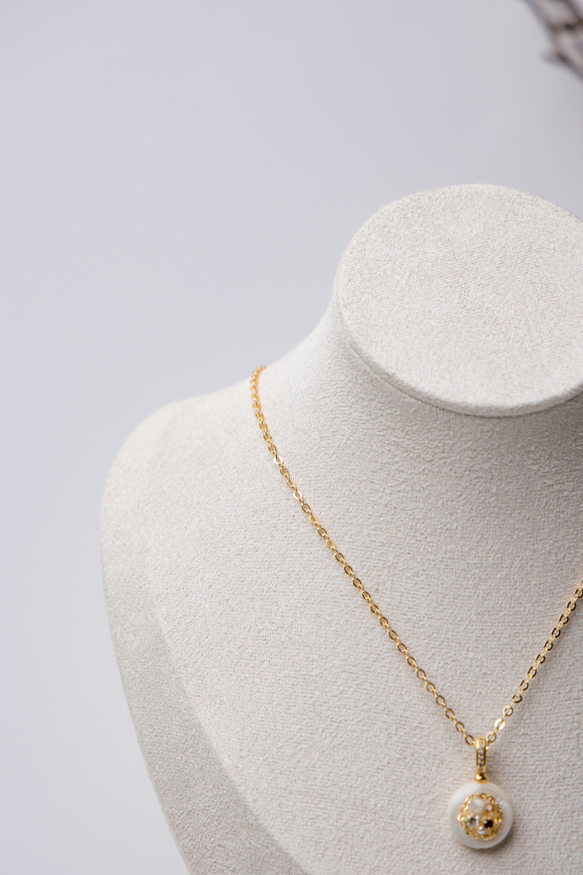 A delicate gold-tone chain necklace featuring a minimalist white resin pendant with embedded stones. Perfect for daily wear and subtle elegance.